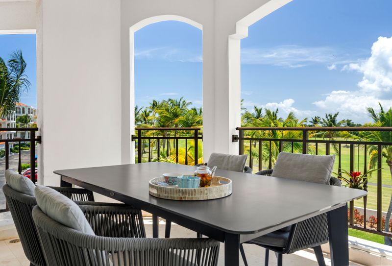 This spacious balcony is a great outdoor spot with a table for four, comfy chairs, and amazing views of the golf course and palm trees. The modern furniture and greenery make it perfect for meals or just soaking in the scenery.