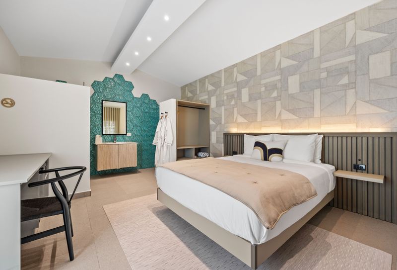 Bright and airy bedroom with a queen-sized bed, a desk, and a closet.