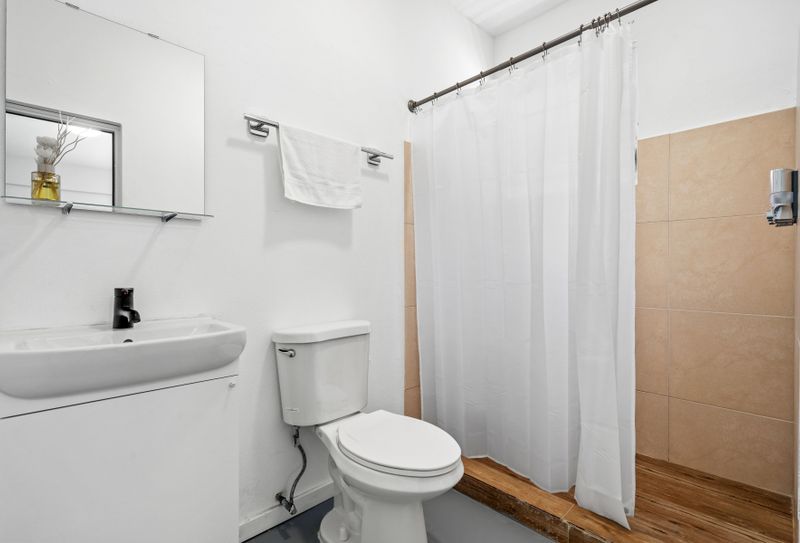 Step into a serene retreat with our well-lit bathroom, boasting a modern sink, full-sized mirror, and spacious shower.