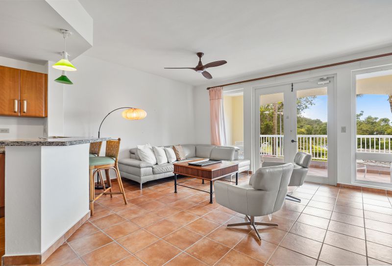livingroom wiht large sofa, seats, ceiling fan, airconditioner, balcony with views,  lamp, open kitchen with countertop