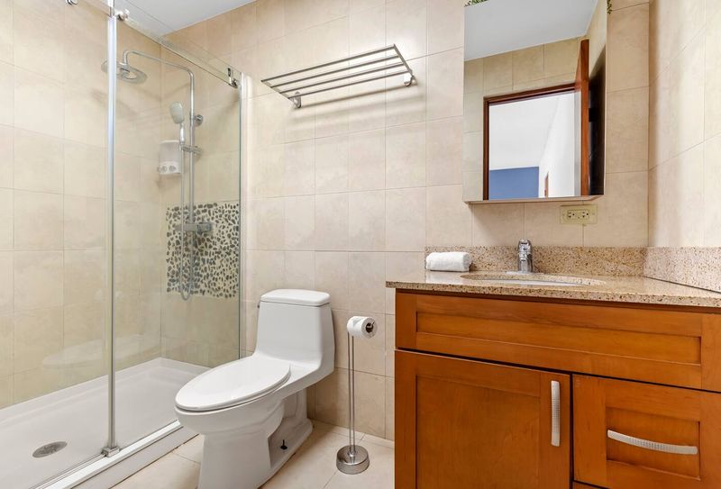 Cacique | Family Vacation Rental 4 A chic and functional bathroom. The elegant wooden vanity and glass shower door combine style and practicality for a comfortable stay.
