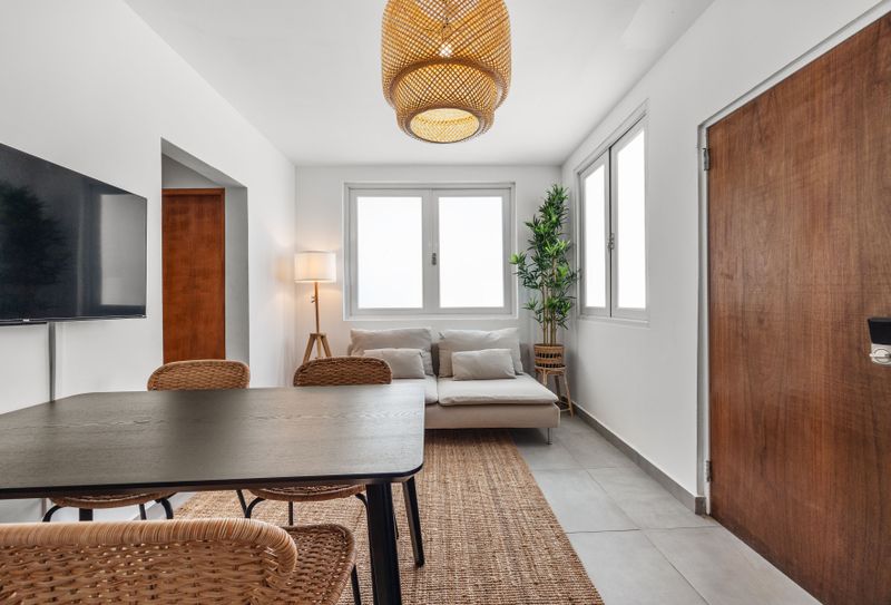 Relax and entertain in this open area, featuring a comfortable sofa, a dining table, and a flat-screen TV for your convenience.