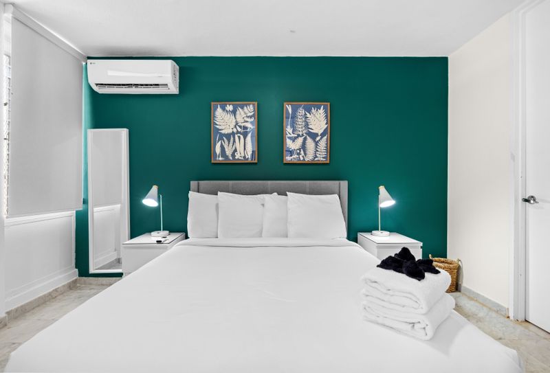 Unwind in elegance with our modern bedroom, featuring a plush king-size bed, a striking green accent wall, and sophisticated decor.