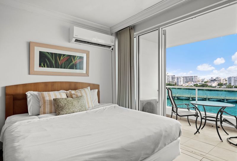 Relax in comfort on your plush, king-sized bed, featuring serene decor and ample light.