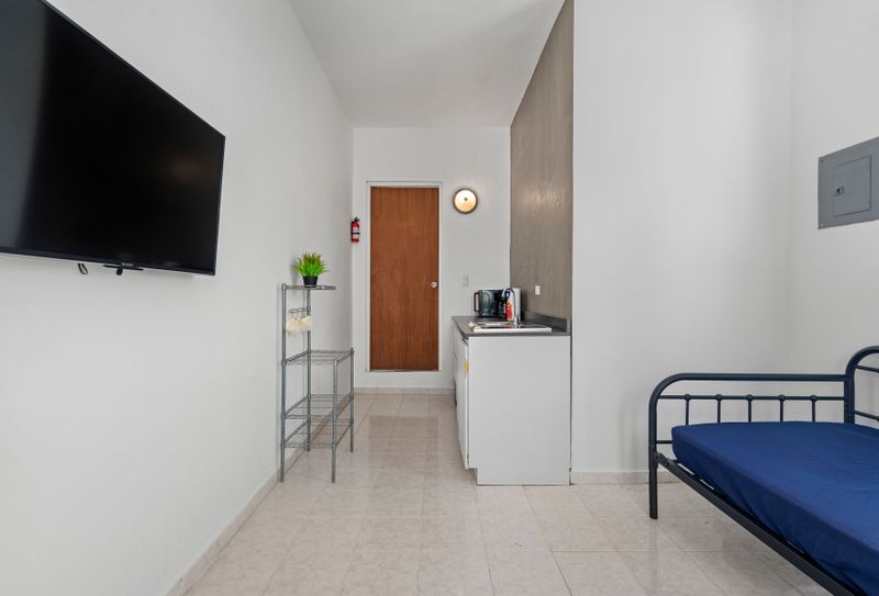 Indulge in your preferred shows on the sleek flat-screen TV, elegantly installed on the immaculate white wall for a refined viewing experience.