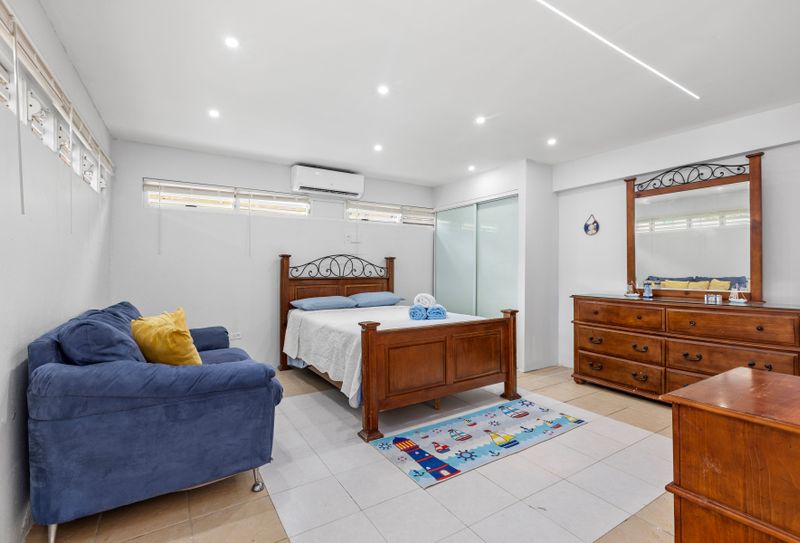 Spacious room with a plush queen-size bed, large vanity mirror, and a cozy sofa. Soft lighting complements the minimalist décor, creating a serene retreat.
