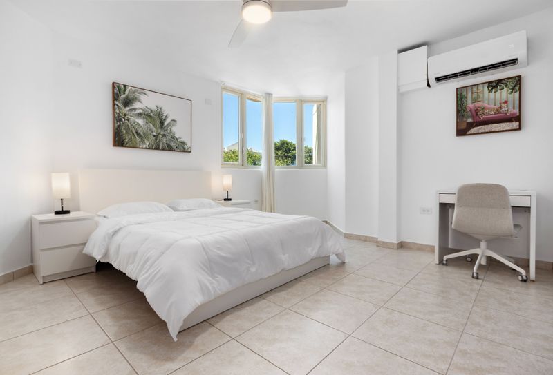 Spacious, sunlit bedroom with comfy bed, AC, and dedicated workspace.