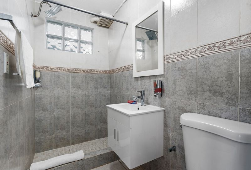 Enter into contemporary elegance with this immaculate bathroom featuring tiled walls and modern facilities.