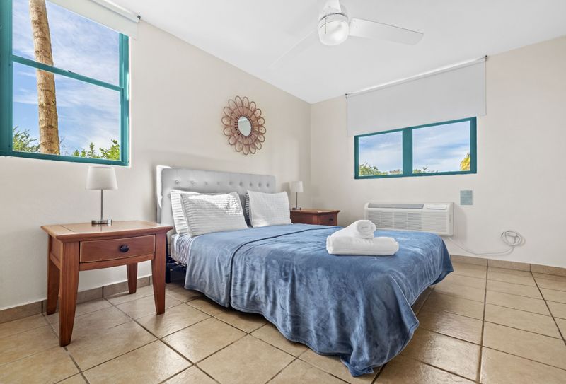 Cozy king sized bedroom with natural light and outdoor views, large wardrobe, soft bed linens, modern bed lamps.