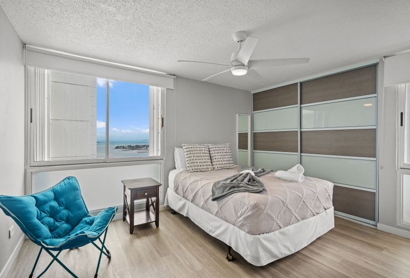 Sleep in comfort with a view! This serene primary bedroom offers a plush queen-sized bed and stunning glimpses of the ocean, ensuring a peaceful and rejuvenating night's sleep.