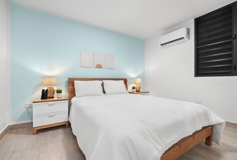 bed with wall art, air conditioner, bedside tables, lamps