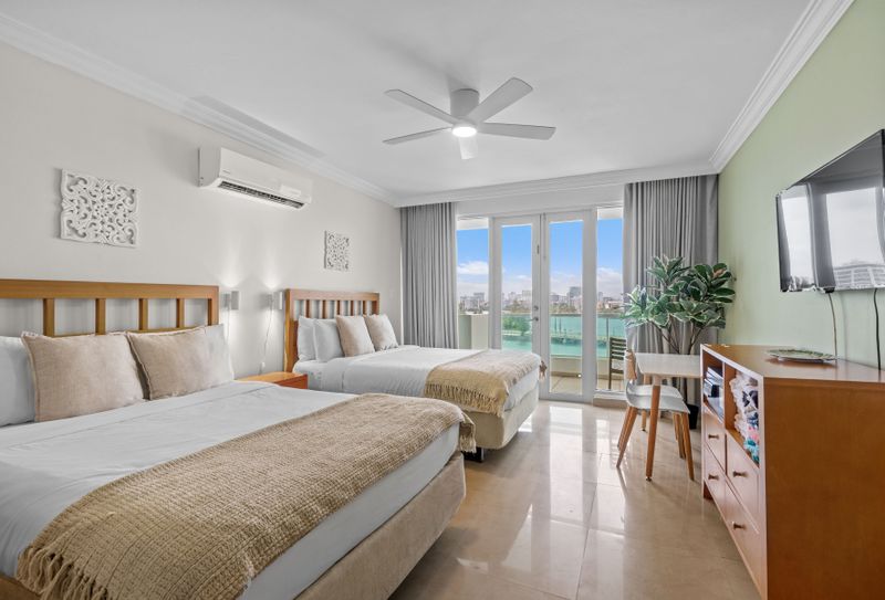 Spacious and inviting bedroom with direct access to a private balcony, offering panoramic water and city vistas.