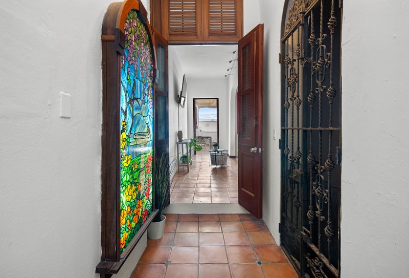 Stroll down the hallway, highlighted by a vibrant stained glass window and an elegant, intricate iron gate.