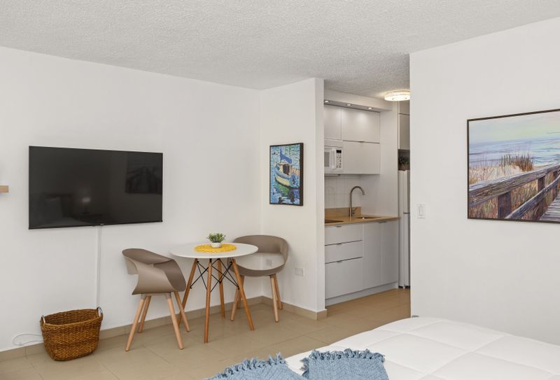 beachfront studio with smart tv, queen sized bed, dining table, and kitchen with appliances and fridge