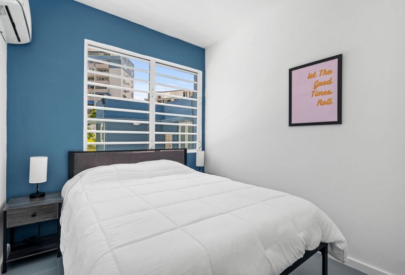 A spacious, sunny room with a blue wall, white rocking chairs, and a world map, offering a comfortable and colorful place to unwind.