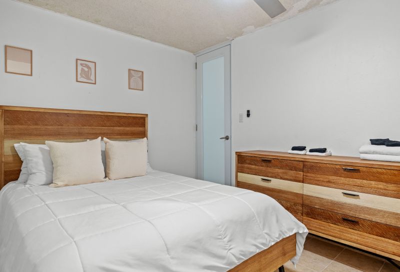 Cozy up in this serene bedroom featuring a sleek wooden bed frame and soft, neutral tones for a restful night's sleep.