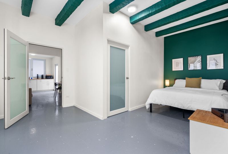 Spacious bedroom with a plush bed, wall-mounted flat screen TV, and a window offering a serene view.