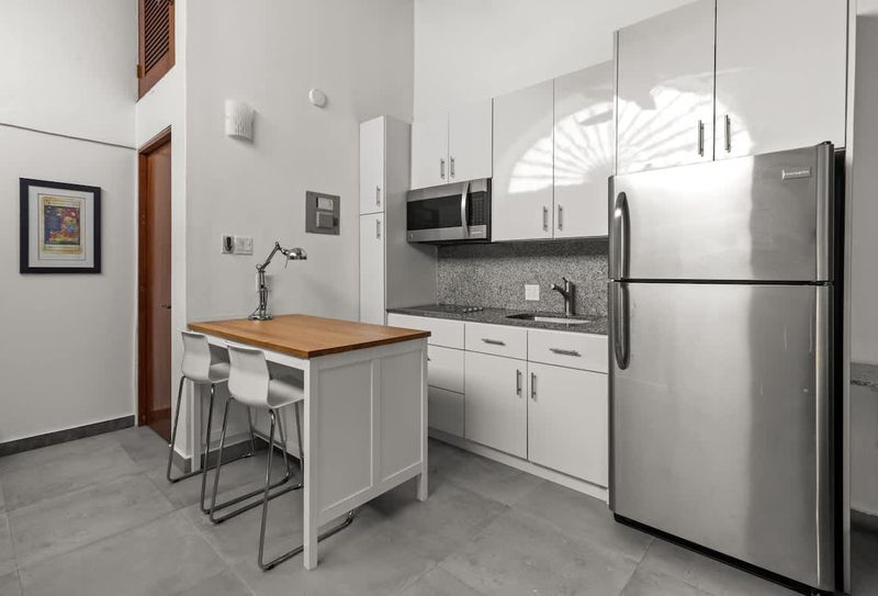 livingroom with kitchen , stainless steel fridge, air conditioner, sofabed, seats, ceiling fan, microwave,  reading lamps, cabinets