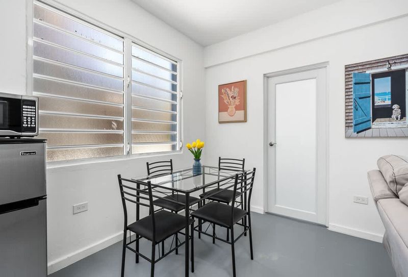 Indulge in comfort and style in this inviting dining space, complete with a sleek modern table set for four, vibrant artwork, and a cozy kitchenette.