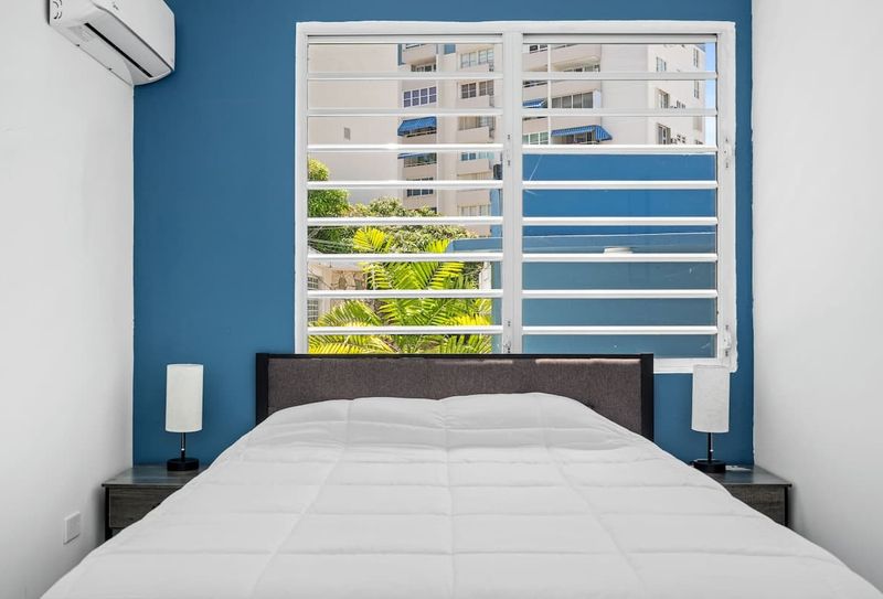 Experience tranquility in this stylish, modern bedroom with a striking blue accent wall and a cozy bed adorned with pristine white linens.