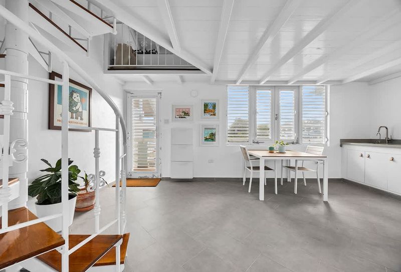 modern kitchen with stainless steel fridge and faucet, dining table and wall art and large windows