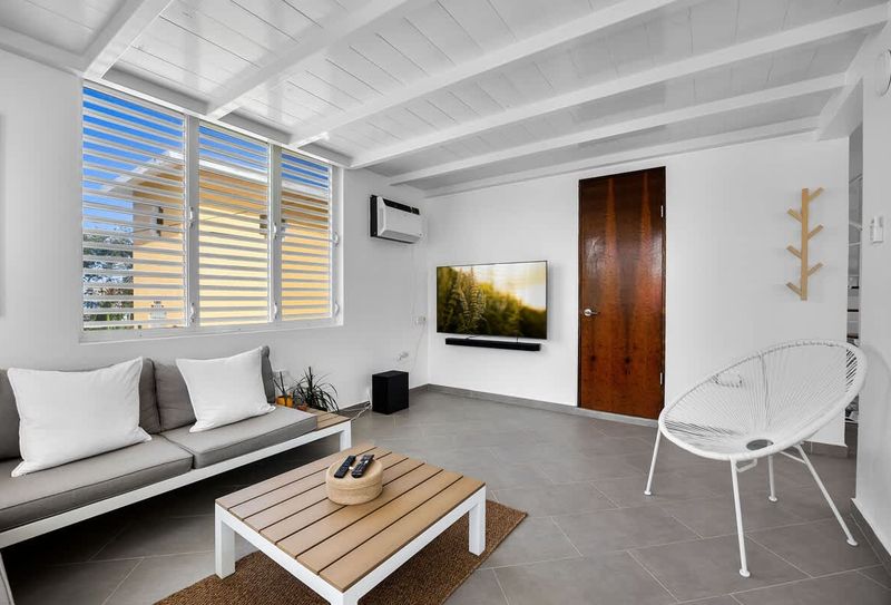 Beachfront House In Puerto Rico 5 Kick back in the sun-filled lounge, featuring a soft sofa and large window – a perfect space to unwind, read a book, or binge your favorite series in comfort.