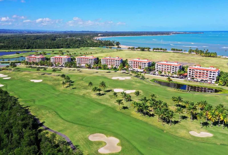 At Grand Reserve | Oceanfront Stay 2 Discover paradise at the Country Club Residences at The Grand Reserve. This stunning aerial view showcases the resort's luxurious accommodations nestled amidst a championship golf course, offering breathtaking vistas of the ocean and lush tropical la