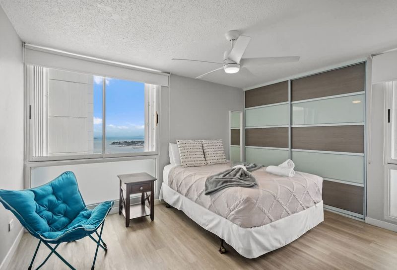 Marina | Beachfront Rental 5 Sleep in comfort with a view! This serene primary bedroom offers a plush queen-sized bed and stunning glimpses of the ocean, ensuring a peaceful and rejuvenating night's sleep.