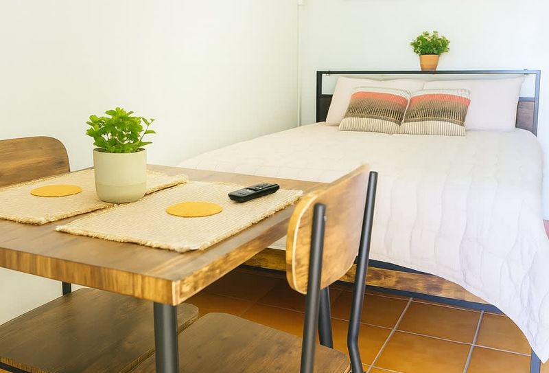 Bright and cozy studio setup with a comfortable full-size bed, wooden dining table for two, and soft neutral decor. Perfect for couples or solo travelers at Luna Suite, Casa Natura.