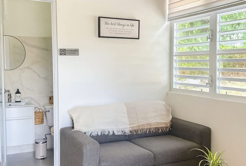 Bright and cozy lounge area with a modern sofa, natural light, indoor plant, and direct access to a clean, stylish bathroom. Perfect for relaxing after the beach at Luna Suite, Casa Natura.