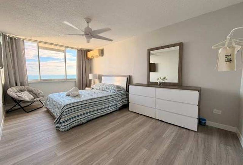 Bedroom with large window with  beachfront views , air conditioner, ceiling fan, mirror, modern storage