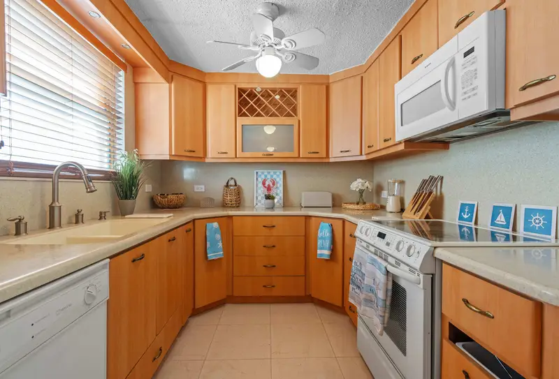 Walk to Beach | Free Parking | Condado 3BR 5 U-shaped kitchen with wood cabinetry, built-in wine rack, white electric range, over-range microwave, dishwasher, double sink and ceiling fan.