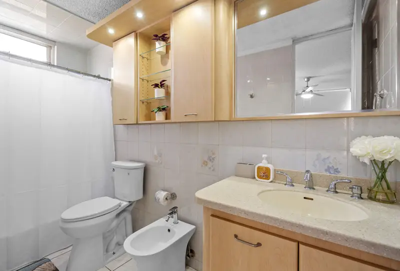 Walk to Beach | Free Parking | Condado 3BR 4 Bathroom with wood vanity, wide mirror, lit glass display shelves, toilet, bidet and tub with white shower curtain.