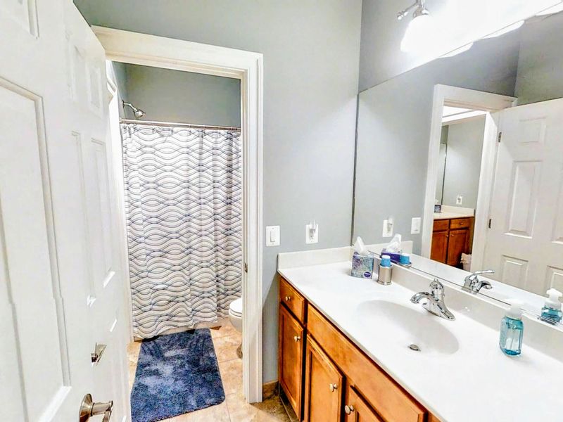 This private en suite bathroom to the queen bedroom features a spacious vanity with dual sinks, a shower/tub combination, and modern decor for a comfortable stay.