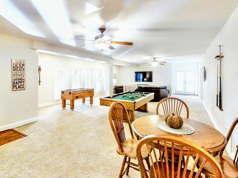 Enjoy the ultimate entertainment space with a spacious game room featuring a pool table, foosball, and a cozy lounge area with a large sectional and TV for movie nights.