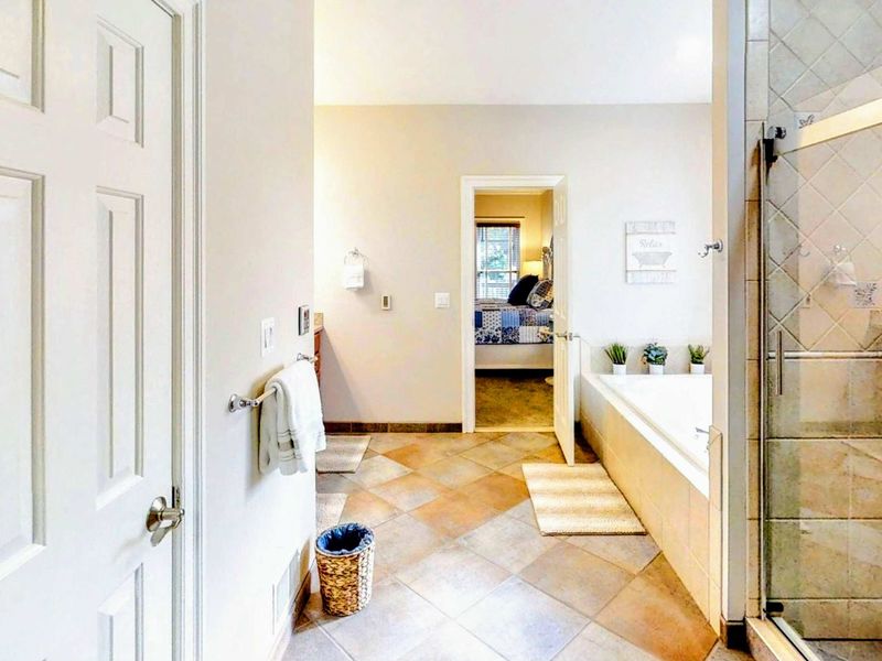 Indulge in the luxurious en suite bathroom of the king primary, featuring a dual vanity, a spacious walk-in shower, and a relaxing soaking tub for ultimate comfort.