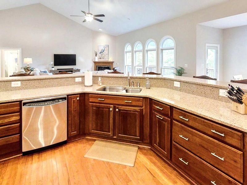 This open-concept kitchen offers expansive granite countertops, a built-in dishwasher, and clear sightlines to the living room—perfect for staying connected while prepping meals.
