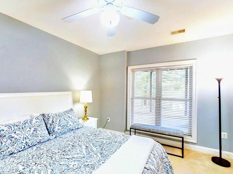 Drift into relaxation in this serene bedroom featuring a comfortable queen bed, soft blue accents, and a bright window nook for a peaceful retreat.