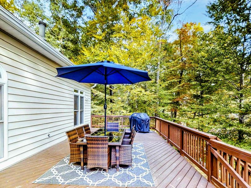 Enjoy outdoor dining on this spacious deck, complete with a shaded seating area, a grill, and stunning views of the surrounding trees and lake.