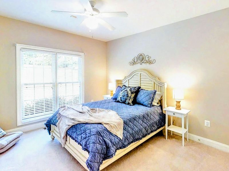 Unwind in this charming and cozy bedroom featuring a plush queen bed, elegant decor, and plenty of natural light for a restful retreat.