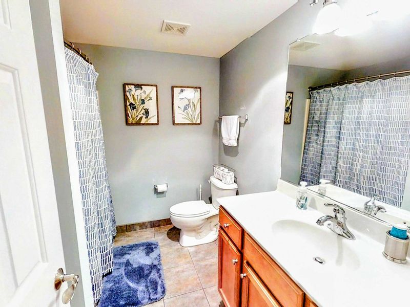 This stylish shared bathroom features a spacious vanity, a shower/tub combination, and modern decor for a comfortable and convenient stay.