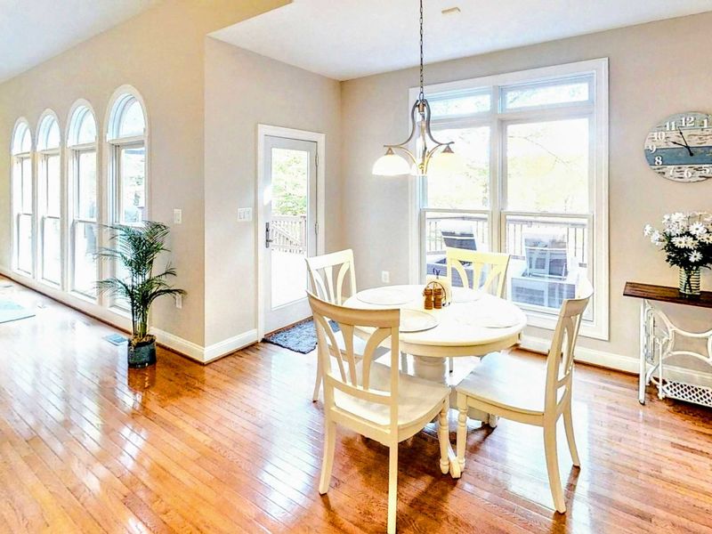 Enjoy meals in this bright and airy dining area, featuring elegant hardwood floors, large windows with natural light, and access to the outdoor deck.