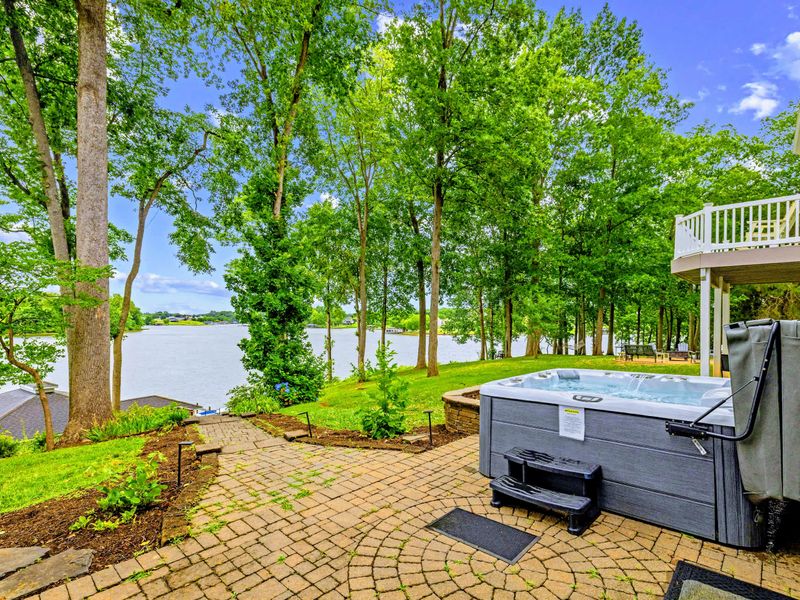 The hot tub sits on a private paver patio overlooking the water.