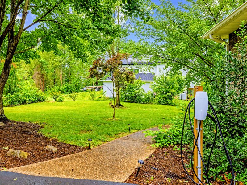 A garden path winds along the side of the home toward the water.