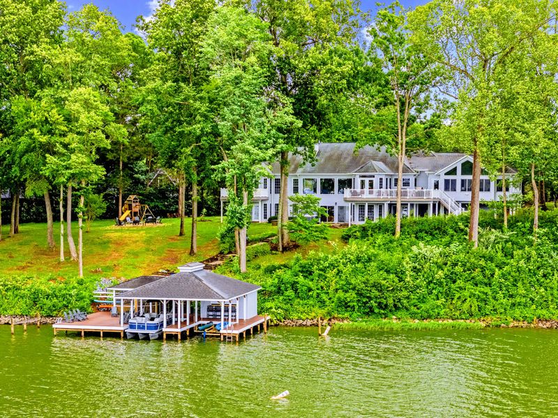 A bird's-eye view of the home, decks, and dock against the cove.