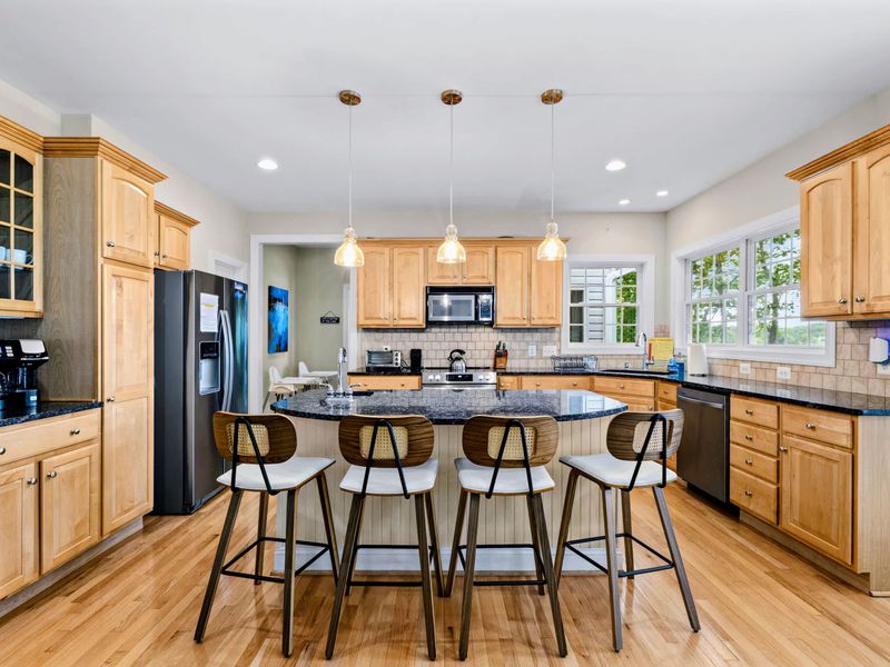 A spacious chef's kitchen with a large island and seating, open to the living space.