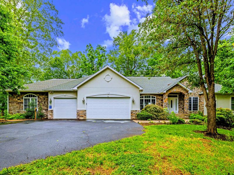 Stone-and-siding curb appeal tucked among mature trees, your home base for the lake week.