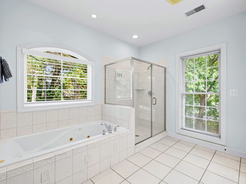 The primary ensuite features a soaking tub and a separate glass shower.