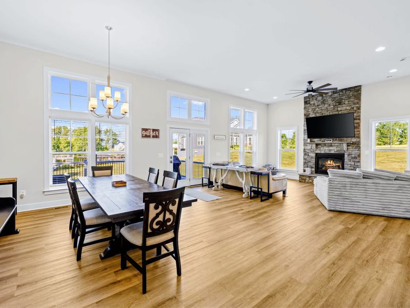 Dining Area - Six-seat farmhouse table anchors the great room beside the stone fireplace, with deck and yard views through the wall of windows.