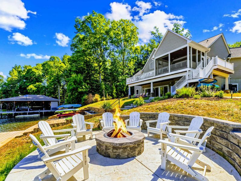 Fire Pit - White Adirondack chairs circle the stone fire pit, the lake glittering just beyond for easy evening gatherings.